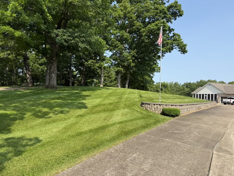 Professional lawn mowing with clean stripes and retaining wall